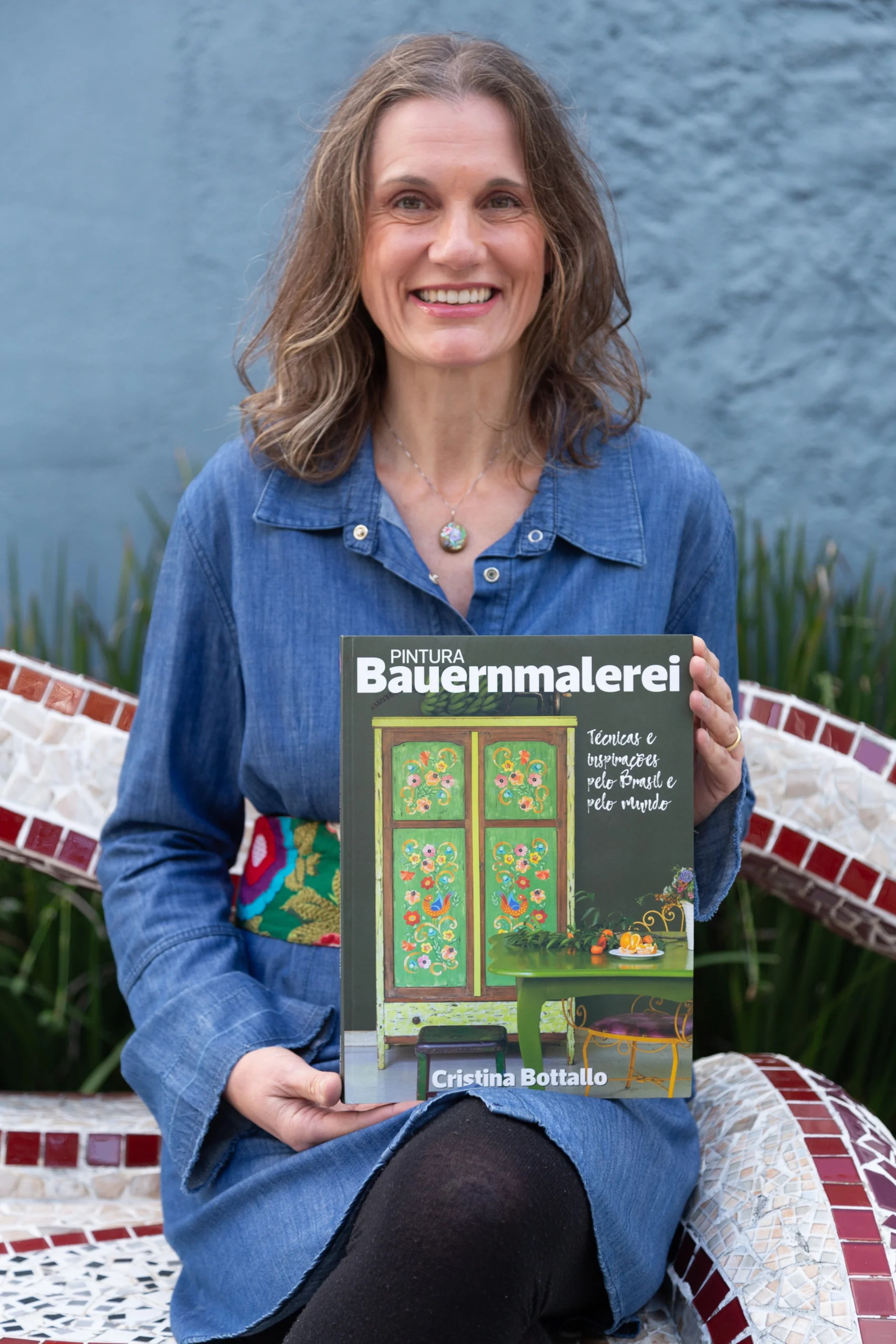 Cristina Bottallo segurando seu livro Pintura Bauernmalerei